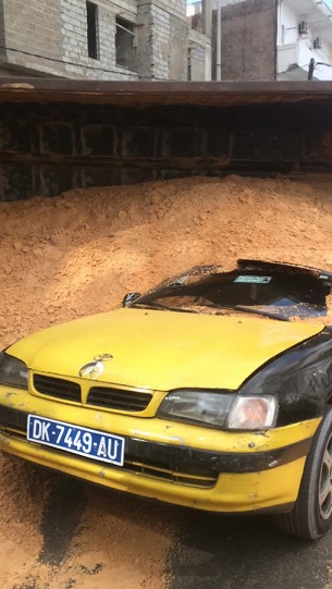 Photos :  La benne d’un camion de sable se renverse sur un taxi. Regardez