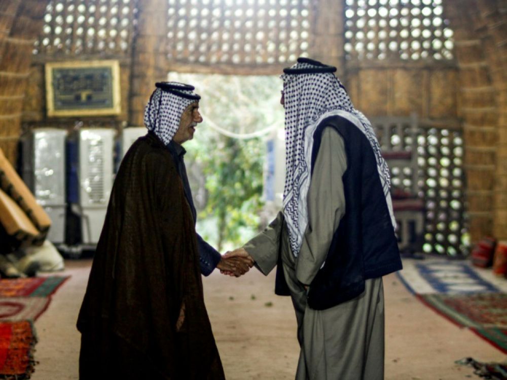 Deux membres des tribus de la province de Najaf dans le sud de l'Irak se serrent la main, le 15 novembre 2018 AFP - HAIDAR HAMDANI