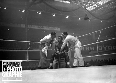 Guerre 1939-1945. Assane Diouf, boxeur français, conseillé par ses soigneurs, lors de son match contre Jean Despeaux. Paris, palais des sports, avril 1941.
