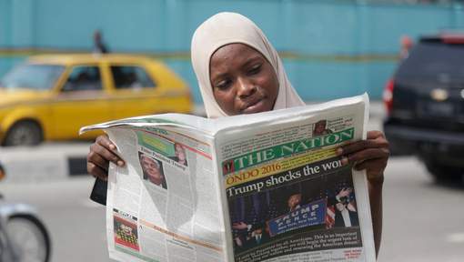 Une femme musulmane lisant un journal qui titre "Trump choque le monde", à Lagos, au Nigeria