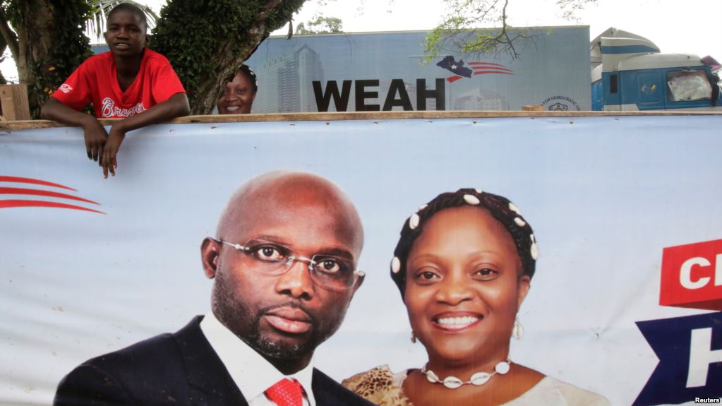 Un partisan de l'ancien footballeur et candidat à la présidence du Congrès pour le changement démocratique (CDC) George Weah se tient derrière une bannière de la campagne présidentielle à Monrovia, Libéria, le 6 octobre 2017.